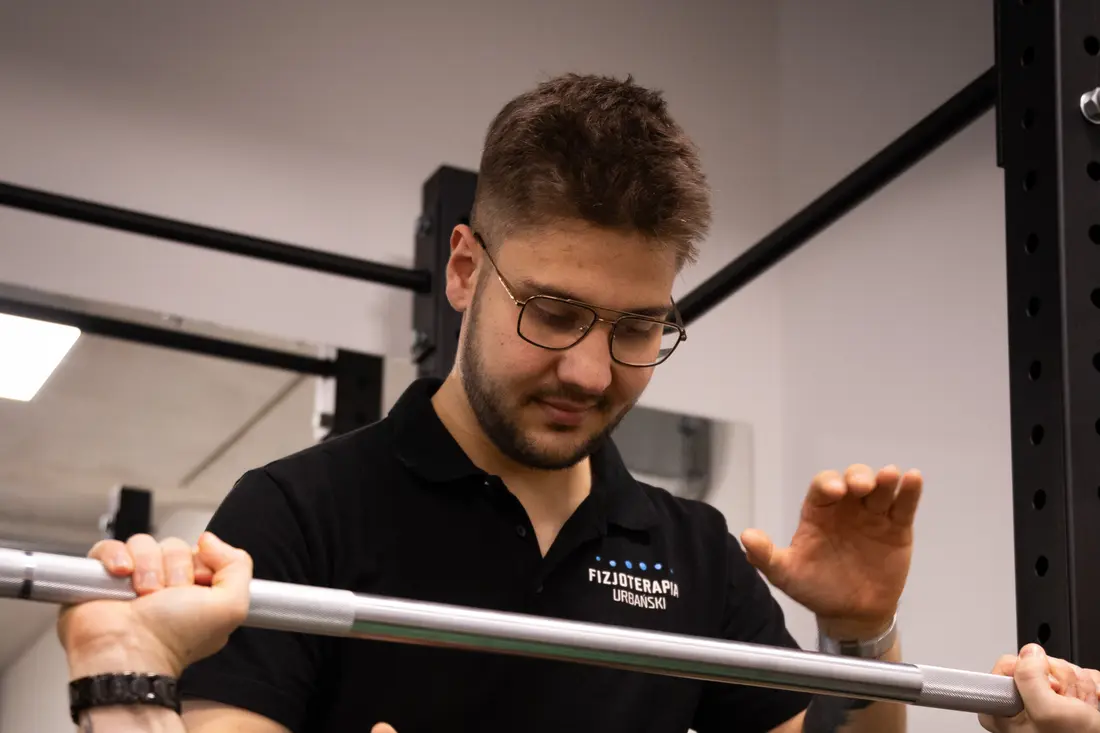 Jakub Gibas asekuruje podopiecznego przy wyciskaniu sztangi