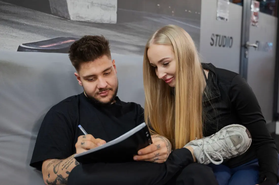 Trener zapisuje plan treningowy w notatniku, siedząc obok podopiecznej